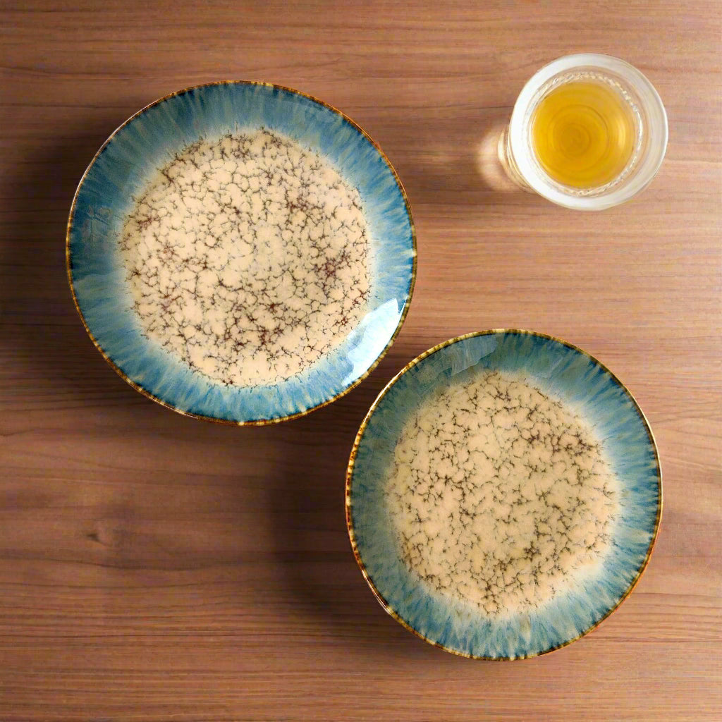 Two ceramic bowls with textured surface on a colorful geometric-patterned fabric.