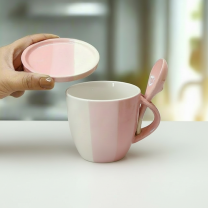 Pink mug with matching spoon and lid held by a hand on a white surface.